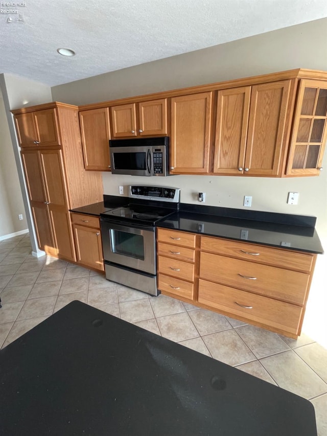 kitchen featuring a textured ceiling, stainless steel appliances, and light tile patterned flooring