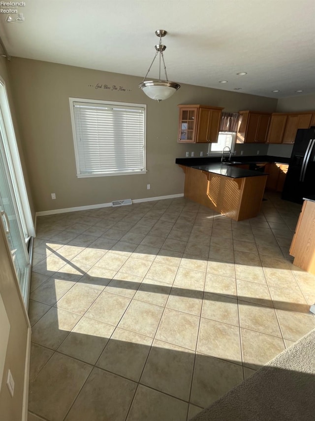 kitchen featuring a kitchen bar, sink, light tile patterned floors, and hanging light fixtures