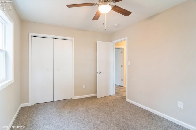 unfurnished bedroom with ceiling fan, light colored carpet, multiple windows, and a closet