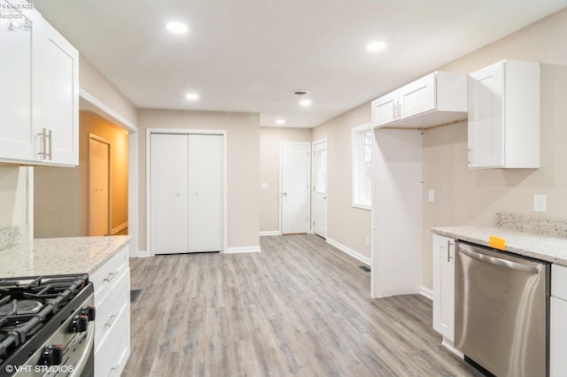 kitchen featuring light stone countertops, stainless steel appliances, white cabinetry, and light hardwood / wood-style floors