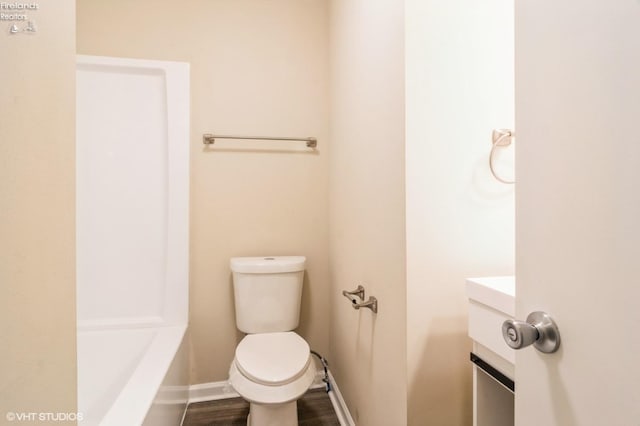 bathroom with a bathing tub, vanity, wood-type flooring, and toilet