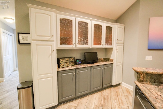 kitchen with dishwasher, light hardwood / wood-style floors, light stone counters, and white cabinetry