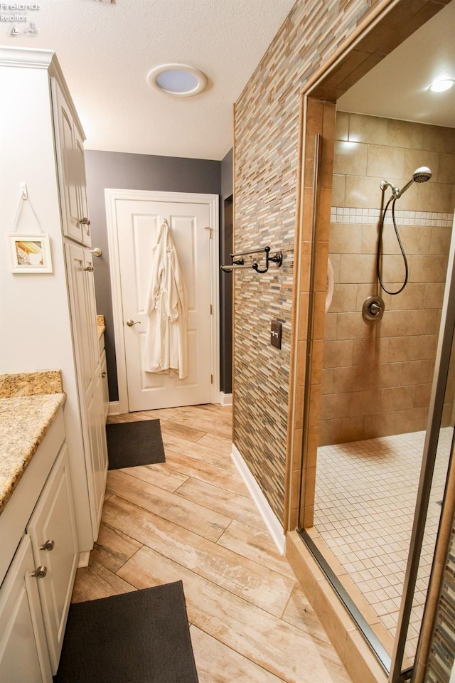 bathroom featuring hardwood / wood-style floors, vanity, and a tile shower