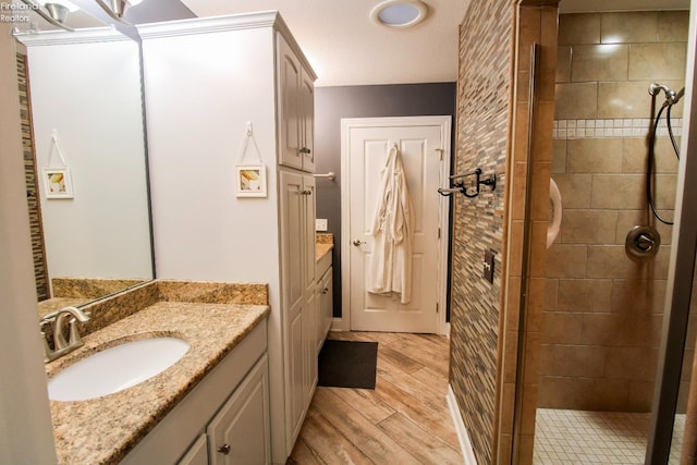 bathroom with a tile shower, vanity, and hardwood / wood-style flooring