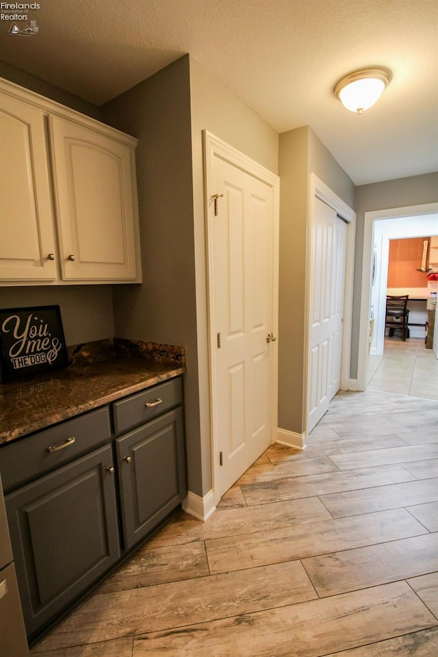 hallway with a textured ceiling and light hardwood / wood-style flooring