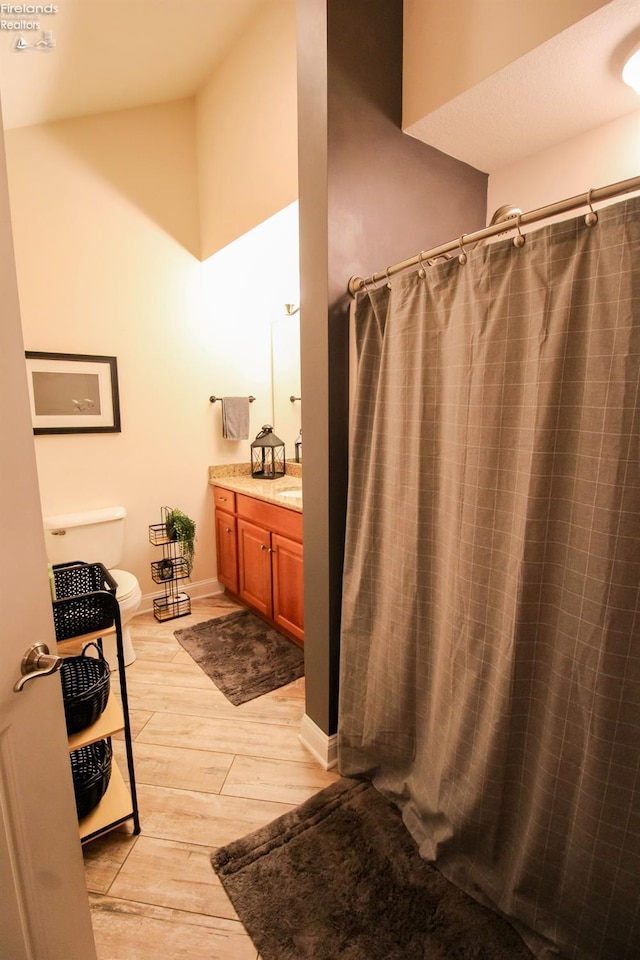 bathroom with curtained shower, hardwood / wood-style floors, vanity, and toilet