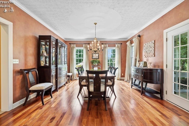 dining room with wood-type flooring, an inviting chandelier, and crown molding