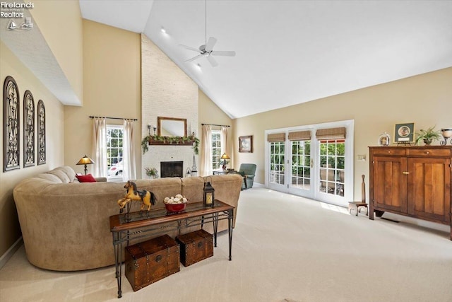 carpeted living room with a large fireplace, plenty of natural light, ceiling fan, and high vaulted ceiling