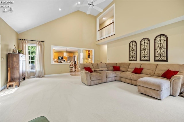 carpeted living room with ceiling fan and high vaulted ceiling