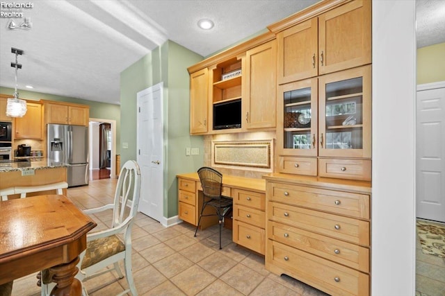 kitchen with light stone counters, decorative light fixtures, light brown cabinetry, light tile patterned floors, and appliances with stainless steel finishes