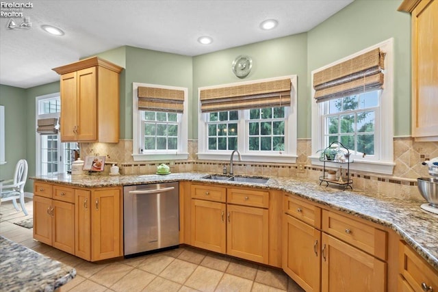 kitchen featuring dishwasher, sink, light tile patterned floors, tasteful backsplash, and light stone counters