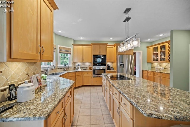 kitchen with light stone countertops, sink, black appliances, a kitchen island, and light tile patterned flooring