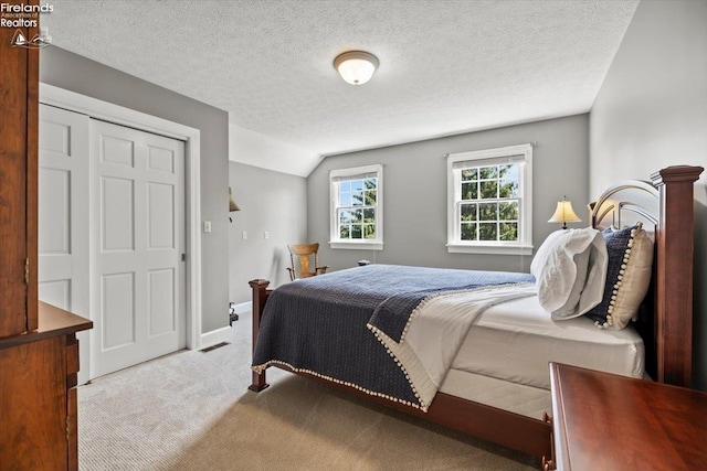 bedroom with a textured ceiling, lofted ceiling, and light carpet