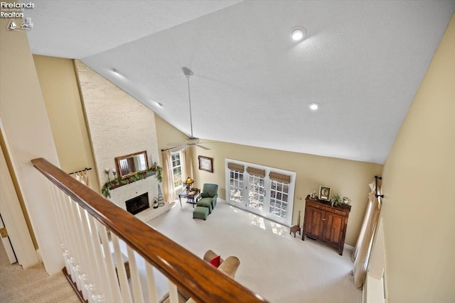 interior space featuring a textured ceiling, vaulted ceiling, ceiling fan, and a stone fireplace