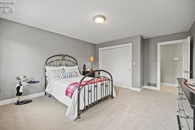 carpeted bedroom with a textured ceiling and a closet