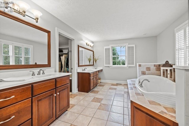 bathroom featuring tile patterned flooring, vanity, a bathtub, and a textured ceiling