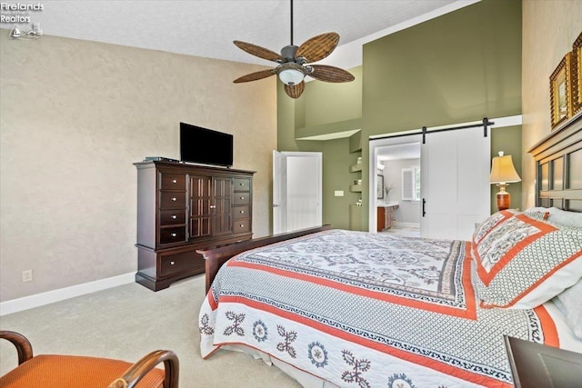 bedroom featuring high vaulted ceiling, ensuite bath, ceiling fan, a barn door, and carpet floors