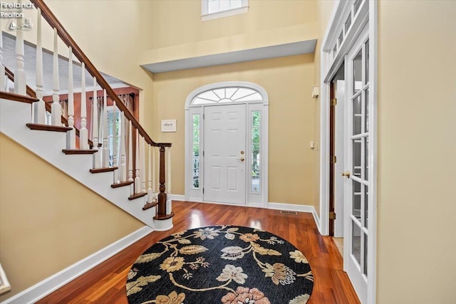 foyer with french doors, a towering ceiling, and hardwood / wood-style flooring