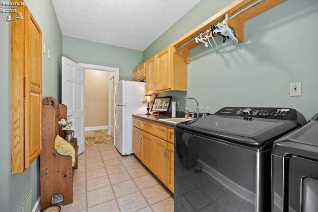 clothes washing area with washer and clothes dryer, light tile patterned flooring, and sink