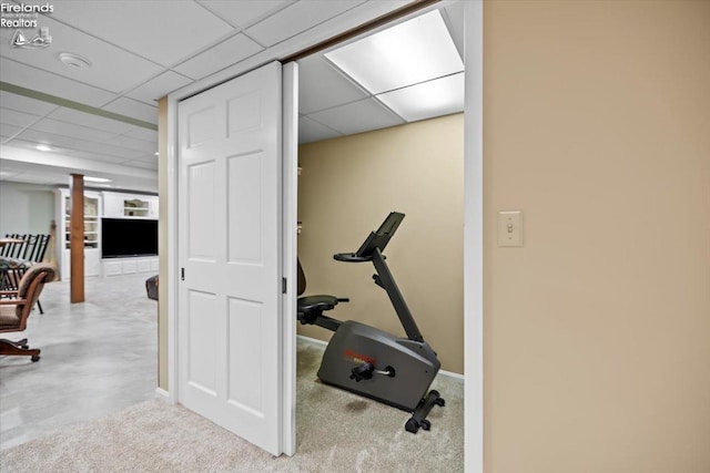 exercise area featuring a paneled ceiling and light colored carpet