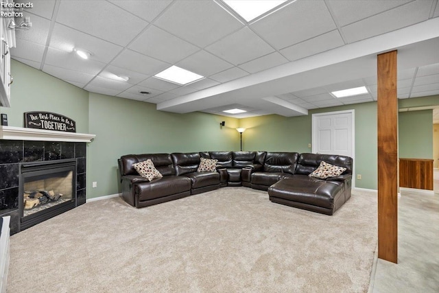 living room featuring a tile fireplace, light carpet, and a paneled ceiling