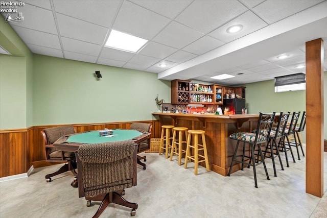 bar featuring a paneled ceiling and black fridge