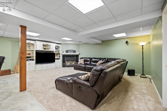 living room with a paneled ceiling, light carpet, a fireplace, and built in shelves