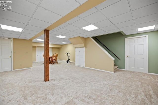 basement featuring a drop ceiling and light carpet