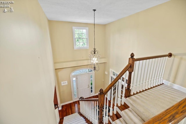 stairway featuring hardwood / wood-style floors and an inviting chandelier