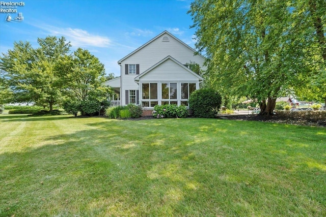 rear view of house featuring a sunroom and a yard