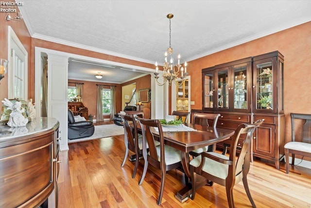 dining area with a chandelier, ornamental molding, and light hardwood / wood-style flooring