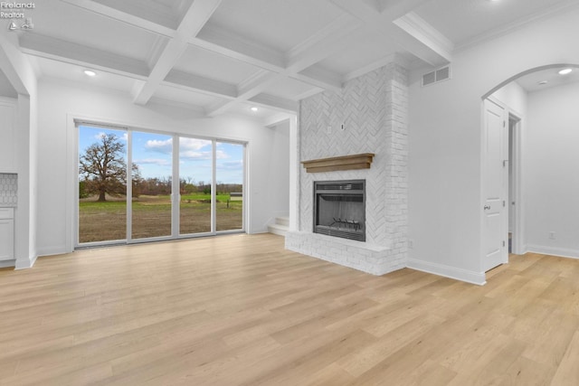 unfurnished living room with beam ceiling, a fireplace, and light wood-type flooring