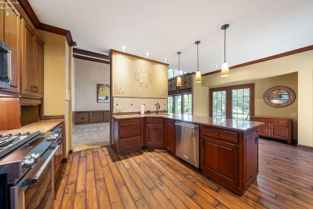 kitchen featuring kitchen peninsula, backsplash, stainless steel appliances, dark wood-type flooring, and pendant lighting