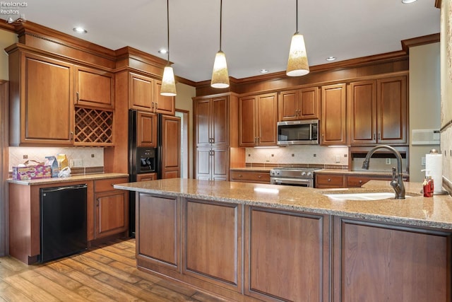 kitchen featuring light stone countertops, sink, crown molding, decorative light fixtures, and appliances with stainless steel finishes