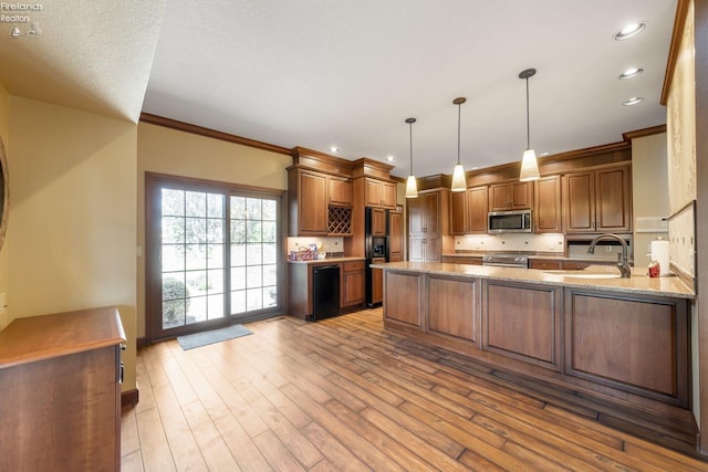 kitchen featuring sink, light stone counters, kitchen peninsula, pendant lighting, and appliances with stainless steel finishes