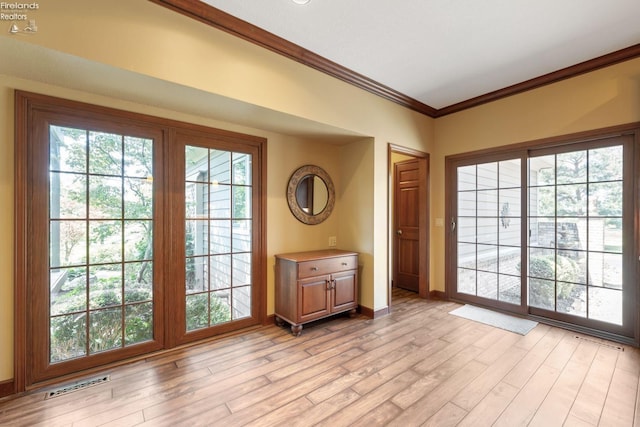 entryway featuring light wood-type flooring and crown molding