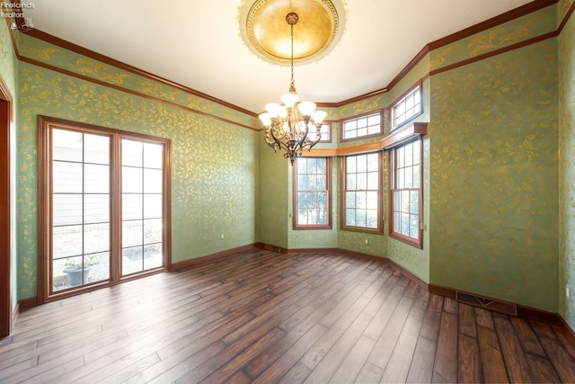 empty room featuring hardwood / wood-style floors, crown molding, and a notable chandelier