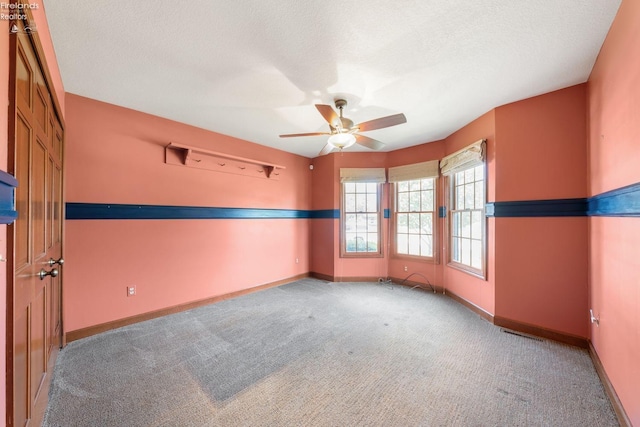 carpeted empty room with ceiling fan and a textured ceiling