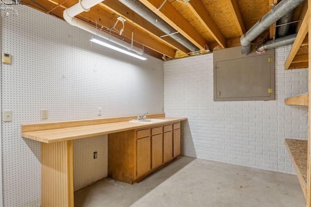 basement featuring brick wall, a workshop area, and sink