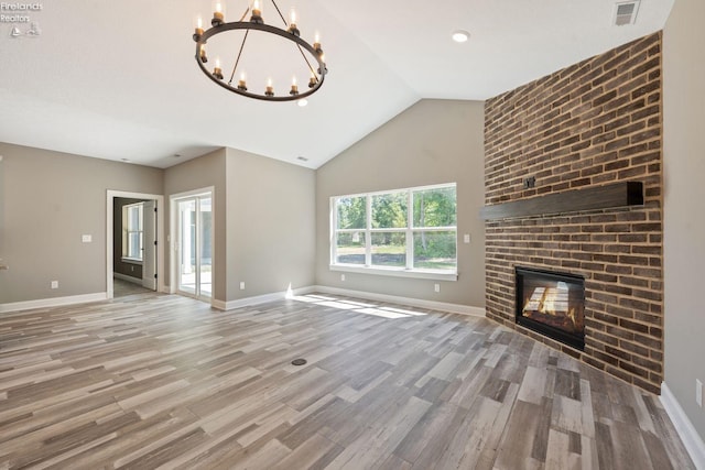 unfurnished living room featuring lofted ceiling, visible vents, a brick fireplace, wood finished floors, and baseboards