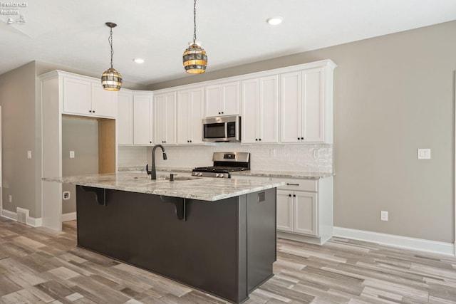 kitchen with decorative backsplash, a breakfast bar area, light stone countertops, stainless steel appliances, and white cabinetry