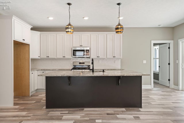 kitchen featuring white cabinets, decorative backsplash, stainless steel appliances, and a sink