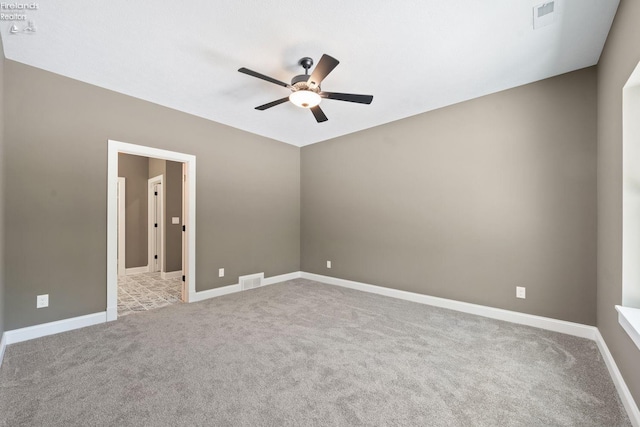 carpeted empty room with ceiling fan, visible vents, and baseboards