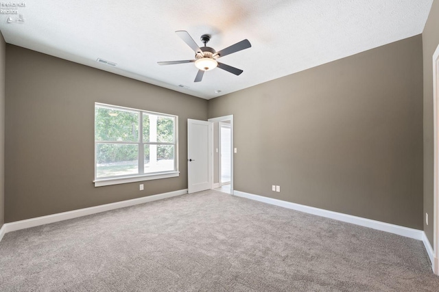 carpeted spare room featuring a textured ceiling, a ceiling fan, visible vents, and baseboards