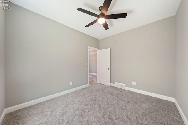 unfurnished room with carpet, visible vents, baseboards, and a ceiling fan