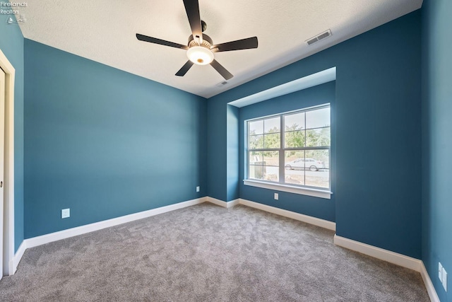 spare room featuring visible vents, carpet flooring, ceiling fan, a textured ceiling, and baseboards