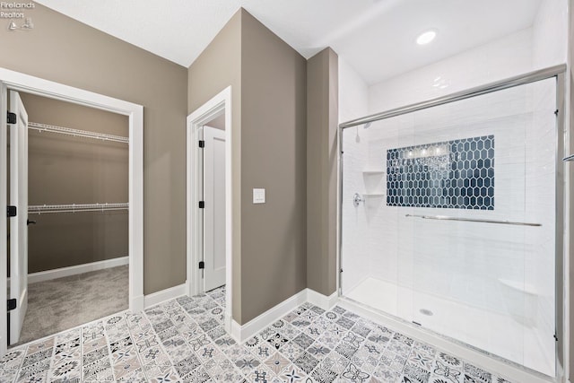 full bath with a shower stall, a spacious closet, baseboards, and tile patterned flooring