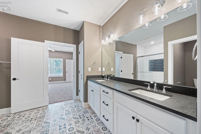 full bathroom with visible vents, a sink, a shower stall, and double vanity