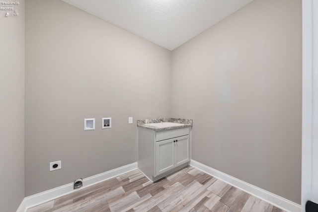 clothes washing area with hookup for a washing machine, hookup for an electric dryer, laundry area, a sink, and light wood-style floors