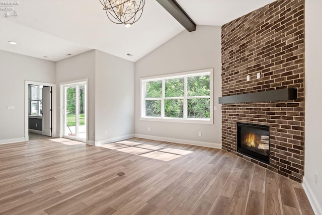 unfurnished living room featuring light wood finished floors, a fireplace, baseboards, and beamed ceiling